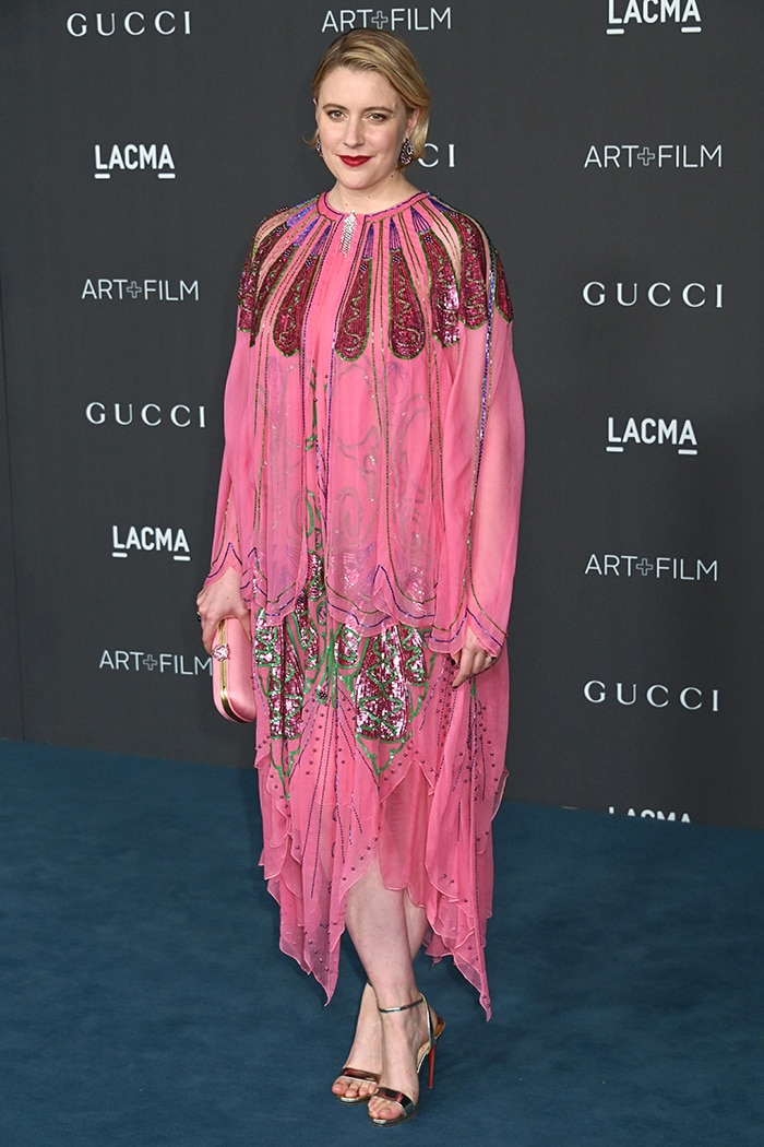 Greta Gerwig embraces whimsical elegance in a pink, bead-embroidered Gucci dress with flowing layers and rich jewel-tone detailing