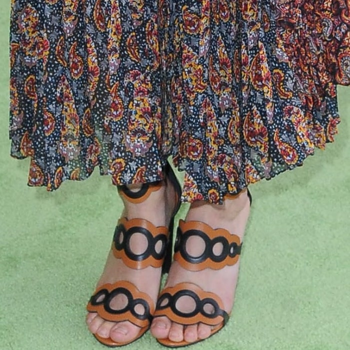 Her Pierre Hardy Saloni sandals—with graphic scalloped straps and a sculptural block heel—anchor the fluid bohemian dress with bold, architectural contrast