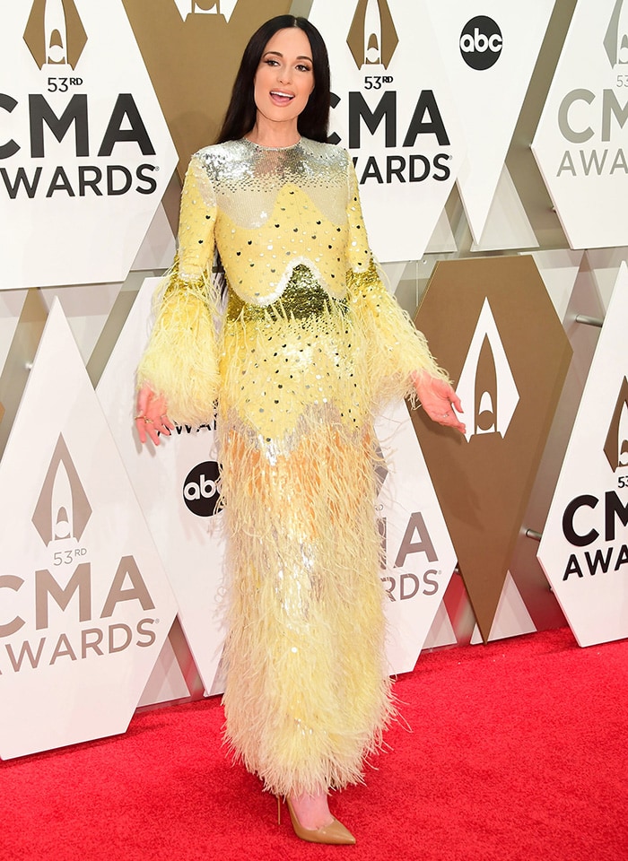 Kacey Musgraves sparkles at the 2019 CMA Awards in a feather-trimmed Valentino Spring 2020 gown, completing the dramatic sequined look with classic tan Christian Louboutin So Kate pumps