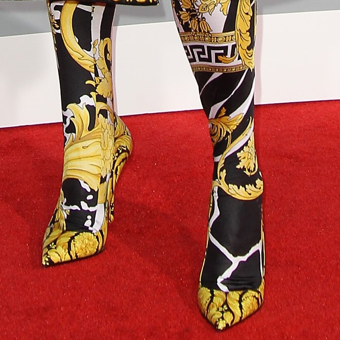 Kesha completes her maximalist red carpet look with pointed-toe Versace Barocco shoes printed in the label’s iconic black-and-gold scroll pattern