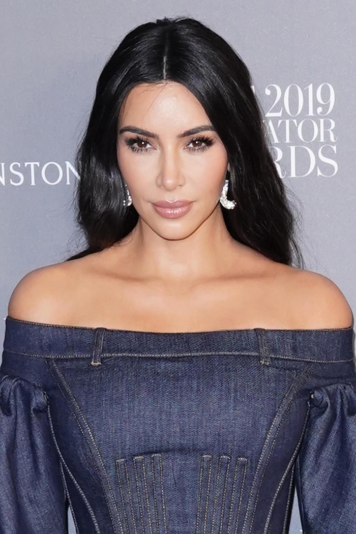 Kim Kardashian wears her long black hair in loose waves with peach makeup and full lashes