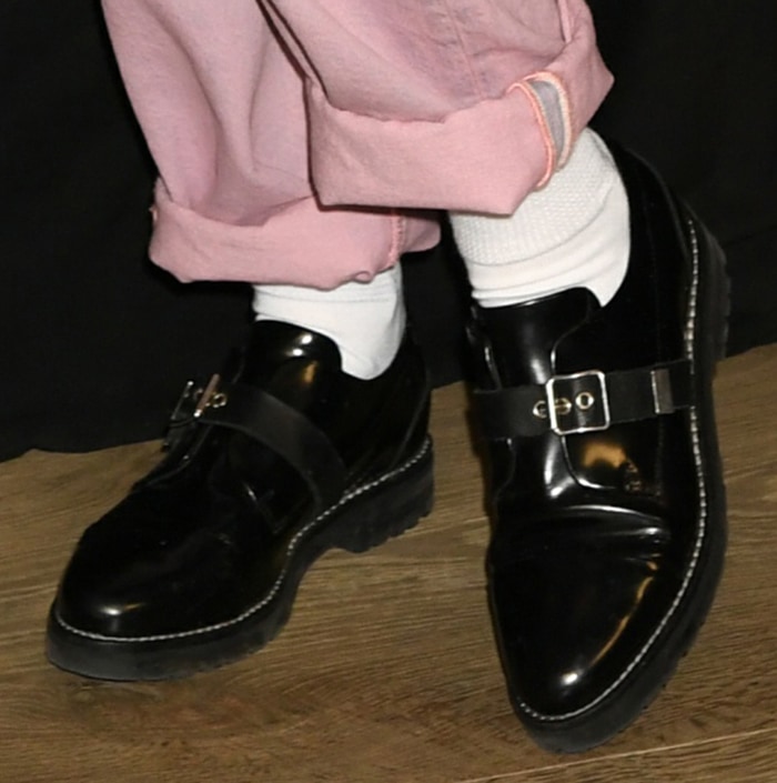 Kristen Stewart finishes her laid-back look with glossy black leather monk-strap creepers, pairing the chunky silhouette with white socks for a sharp, androgynous edge
