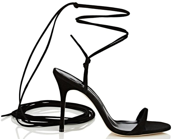 Manolo Blahnik’s Prishipla sandals feature sleek black suede, ultra-fine wraparound ankle ties, and a sculptural stiletto heel designed to elongate the leg with elegant minimalism