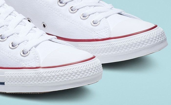 Authentic white Converse Chuck Taylor All Star sneakers featuring the signature solid rubber toe caps and textured diamond toe guards