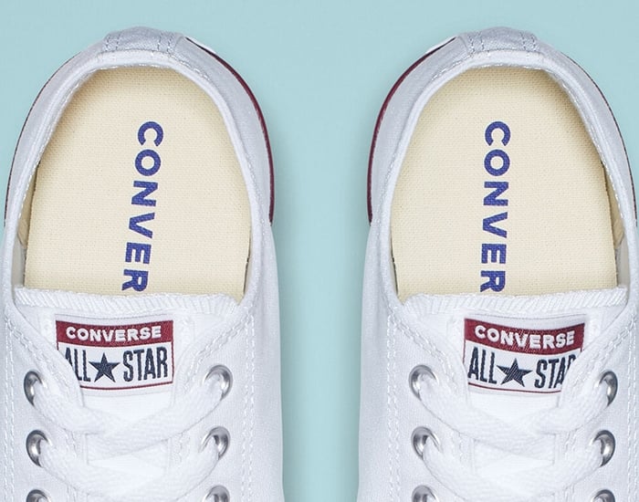 The inner soles of authentic white Converse Chuck Taylor All Star sneakers, featuring the signature navy “CONVERSE” print