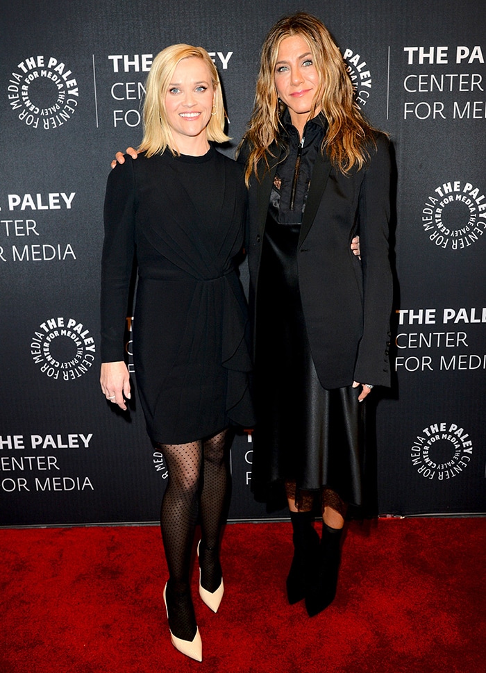 Standing beside Jennifer Aniston, Reese Witherspoon’s polka-dot tights and pointed pumps subtly emphasize their real-life height contrast