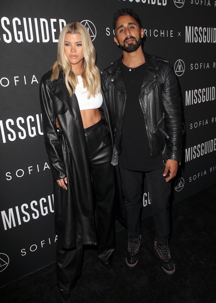 Sofia Richie pairs a black faux-leather trench and matching trousers with a white ribbed crop top and sharp Balenciaga Square Knife pumps as she poses with Nitin Passi at her Missguided collection launch at Bootsy Bellows in West Hollywood on September 18, 2019