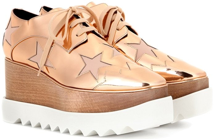 The metallic gold Stella McCartney “Elyse” derby shoes paired masculine-inspired lace-ups with an exaggerated platform sole, combining a sustainable wooden wedge and serrated rubber outsole with the brand’s signature sculptural proportions
