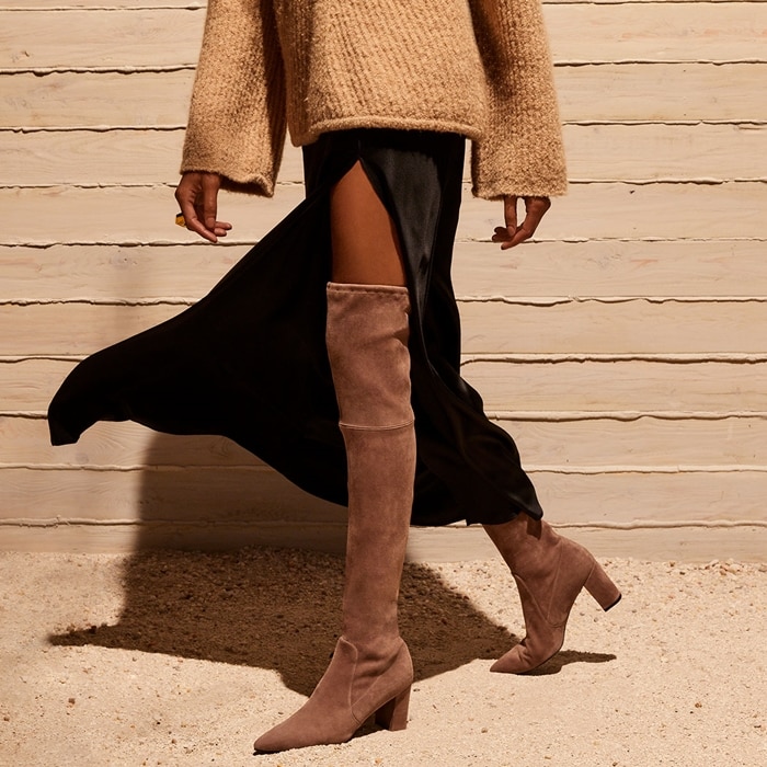 A pair of taupe suede Stuart Weitzman over-the-knee boots adds soft texture and understated height to a flowing black skirt and oversized knit layers