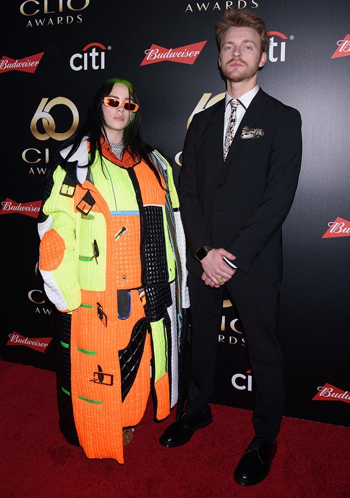 Billie Eilish leans into exaggerated proportions in a patchwork “Keep Going” Rubik’s Cube suit, grounding the oversized silhouette with chunky black shoes, while her brother Finneas O’Connell keeps it sharp in a tailored suit at the 60th Annual Clio Awards on September 25, 2019