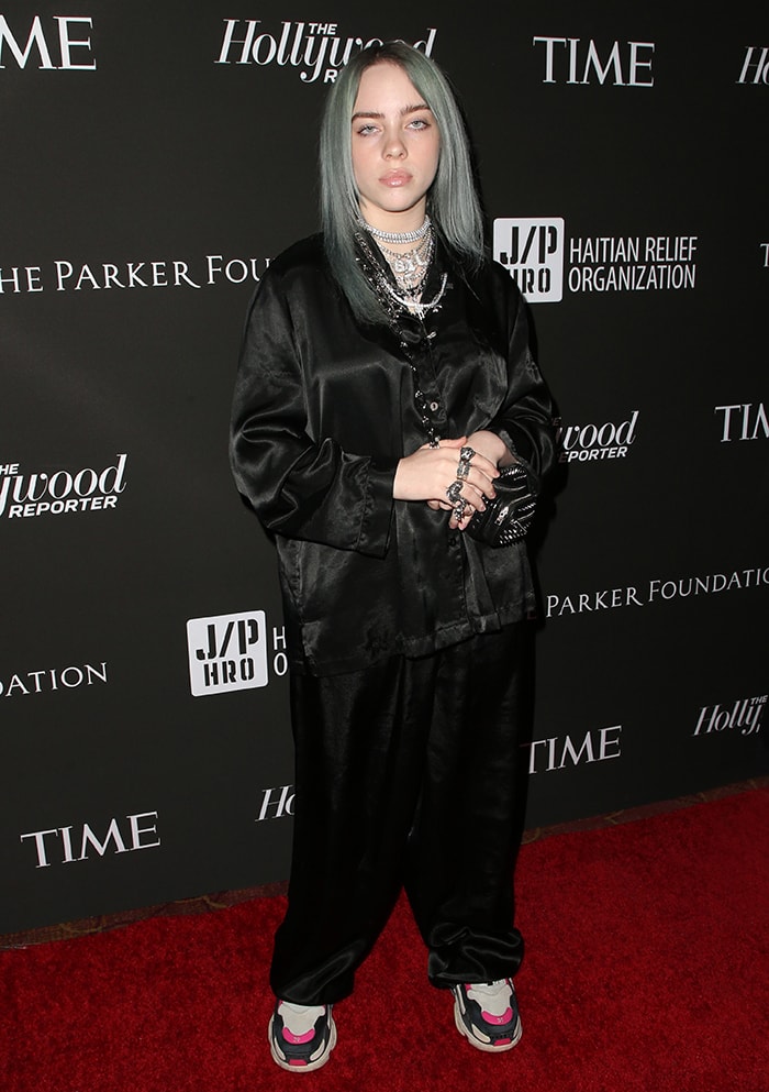 Billie Eilish contrasts a fluid black satin set with chunky, multi-panel sneakers, using their layered sole and color-blocked accents to ground the oversized silhouette at Sean Penn’s CORE Gala in Los Angeles on January 6, 2019