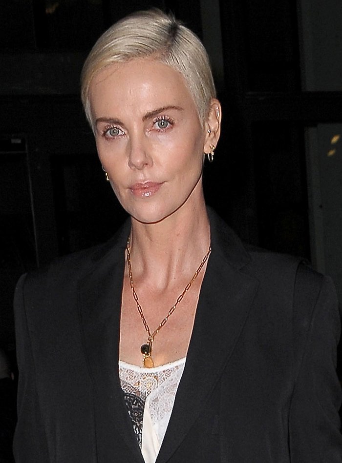 Charlize Theron’s cropped platinum pixie, minimal makeup, and delicate gold jewelry underscore the clean sophistication of her tailored look