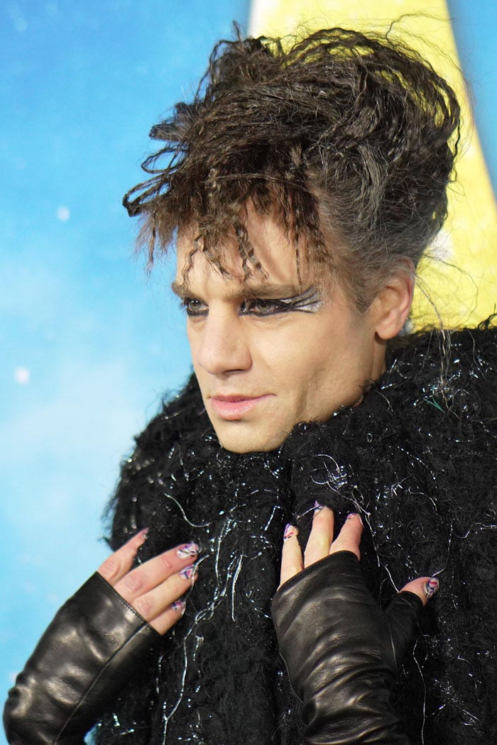 Jordan Roth rocking crimped cat-ear hair, extended cat-eye makeup, and abstract line nail art mimicking the colors on his Viktor Rolf coat