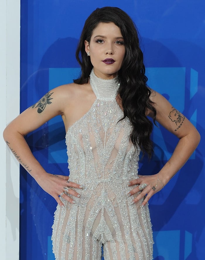 Halsey confidently turns heads at the 2016 MTV Video Music Awards in a sheer, embellished Yousef Al-Jasmi jumpsuit featuring a halter neckline and nude illusion lining, paired with bold plum lips and silver accessories