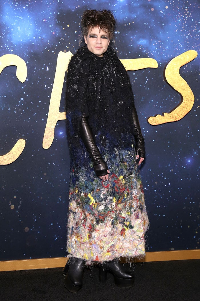 Jordan Roth embraces theatrical glamour at the Cats premiere in a Viktor Rolf Fall 2019 Couture coat crafted from dense felt wool in a striking black-to-multicolor gradient, styled with sleek black platform boots and dramatic cat-eye makeup