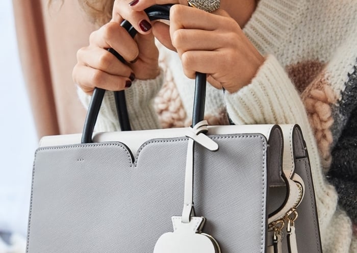 A modern Kate Spade top-handle bag in soft gray Saffiano leather — complete with the brand’s signature heart-shaped trim and polished hardware for a refined, feminine finish