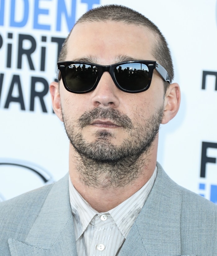 Actor Shia LaBeouf pairs sleek black Ray-Ban sunglasses with a tailored Gucci suit, delivering a sharp, minimalist red-carpet look