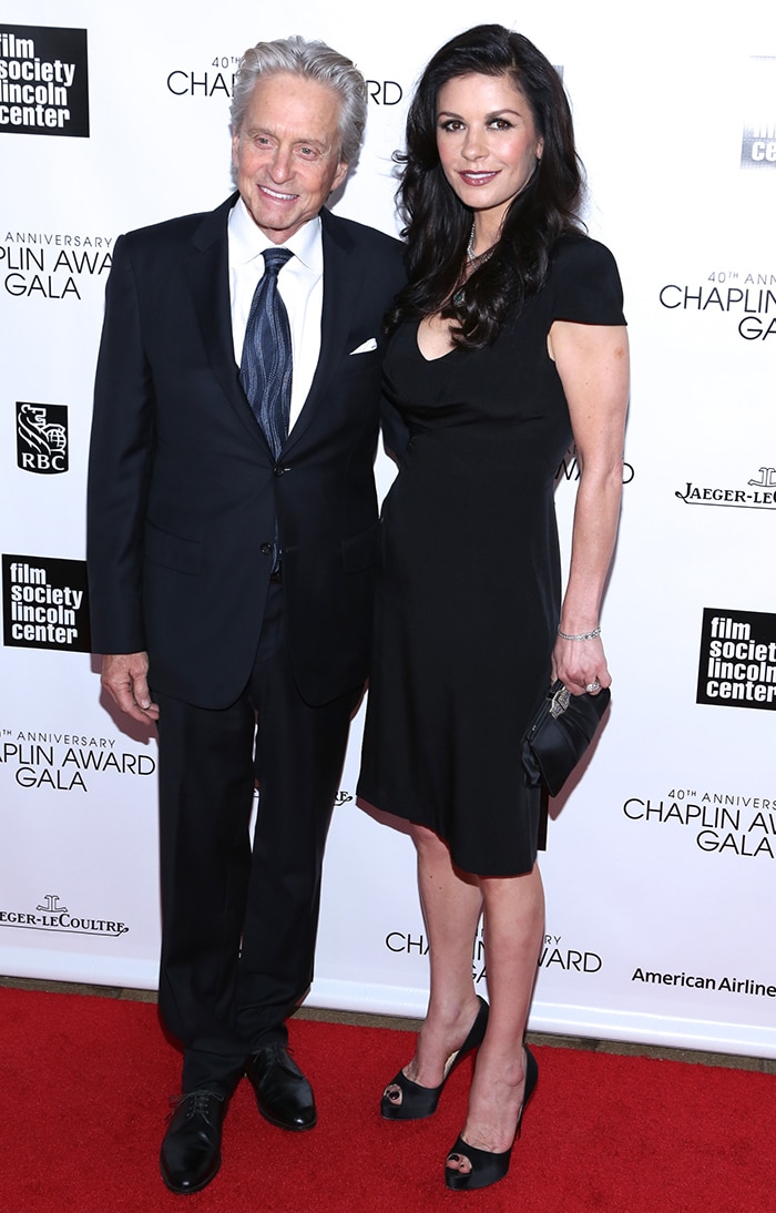 Michael Douglas and Catherine Zeta-Jones arrive at the 40th Annual Chaplin Award Gala in New York City on April 22, 2013, with Zeta-Jones showcasing timeless elegance in a black cap-sleeve cocktail dress styled with peep-toe platform pumps, while Douglas opted for a sharply tailored navy suit and silk tie