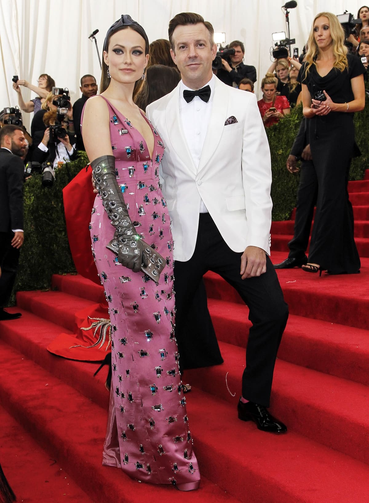 Olivia Wilde stepped onto the 2015 Met Gala red carpet in a pink, crystal-embroidered Prada gown, finishing the look with sleek platform heels and Solange Azagury-Partridge earrings, alongside Jason Sudeikis in a sharp white Prada tuxedo