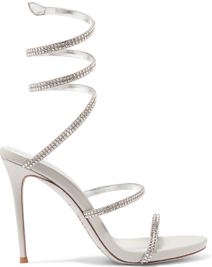 Lizzo's white René Caovilla Cleo sandals peek through the thigh-high slit, their crystal-wrapped ankle coils echoing the Swarovski embellishments on her Versace gown