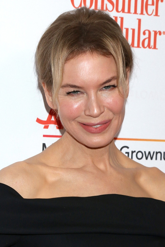 Renée Zellweger pulls her hair up in a chic bun and wears rosy lipstick and blush