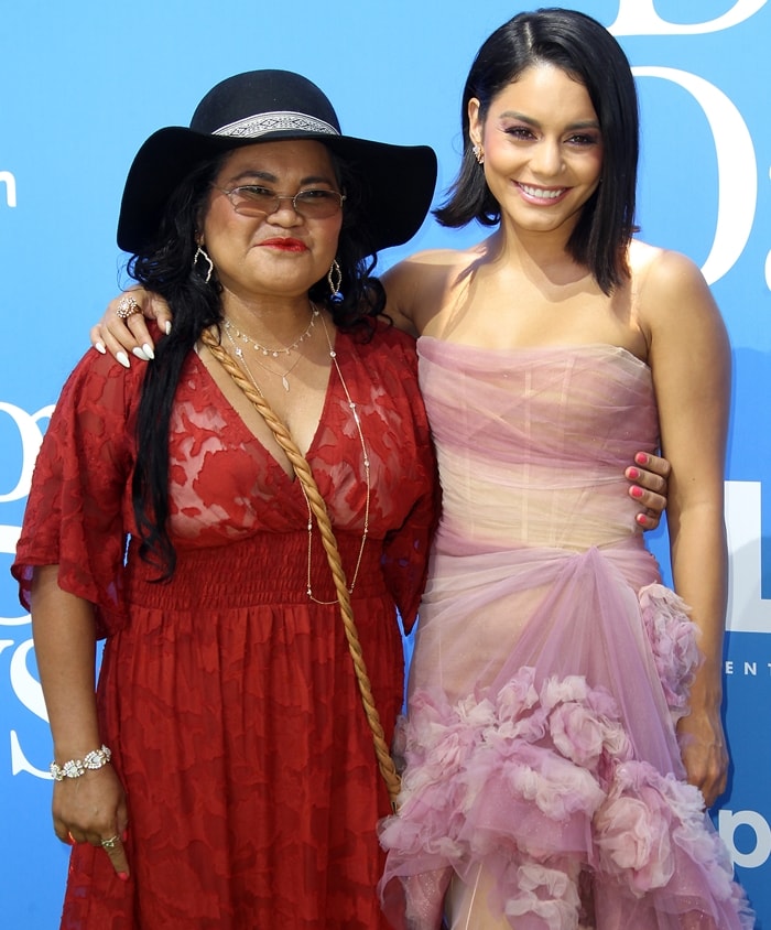 Vanessa Hudgens poses with her mother, Gina Guangco, both showcasing their unique styles—Vanessa in a pastel pink ruffled gown and Gina in a bold red lace dress with a wide-brimmed hat