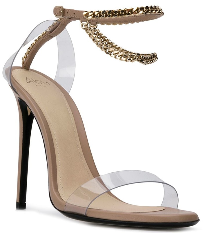 The Alevi Milano 'Valentina' sandal combines barely-there plexi straps with draped gold chain ankle wraps and towering stiletto heels, creating a glamorous barely-there silhouette that perfectly balances modern minimalism with red-carpet sparkle