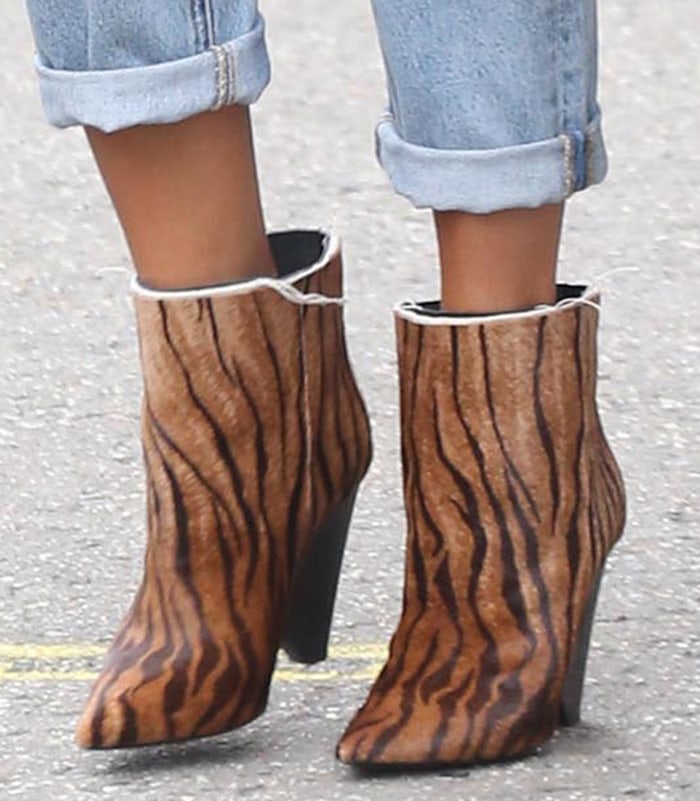 A close-up of Chrissy Teigen's Saint Laurent 'Niki' ankle boots showcases the striking zebra-print calf hair, pointed toes, and sculptural cone heels