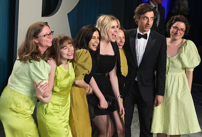 Greta Gerwig and Noah Baumbach share a joyful moment with friends in coordinating yellow-green looks at the Vanity Fair Oscar Party following the 92nd Academy Awards
