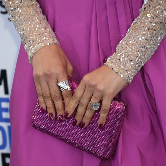 Jennifer Lopez accessorized her Valentino ensemble with an ultra-glam magenta Judith Leiber clutch, fully encrusted with crystals and perfectly matched to her manicure—an elegant finishing touch that highlighted her dazzling rings and sequined sleeves