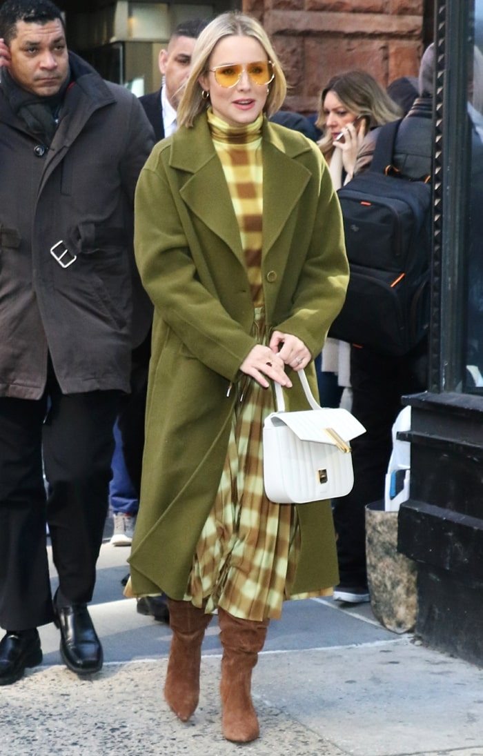 Kristen Bell layered an olive-green Proenza Schouler coat over a blurred-check turtleneck dress and styled the look with slouchy brown Villa Rouge “Baden” suede boots, whose pointed toes and soft texture brought structure and warmth to the tonal outfit during her February 21, 2020, appearance in New York City