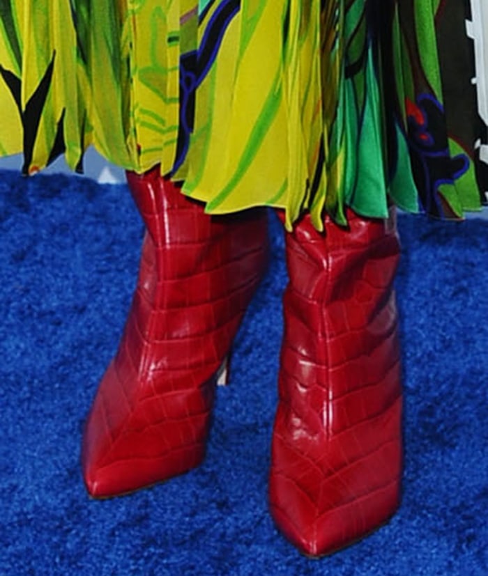 Laura Dern grounded her flowing Valentino dress with a pair of pointed-toe red Schutz “Maryana” boots in a croc-effect finish, adding a sharp pop of color against the dress’s vivid green leaf print