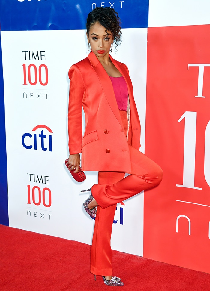Liza Koshy elevates her fiery red pantsuit with glittering pointed pumps, using the sharp toe and shimmering finish to lengthen her legs and add a high-impact, red-carpet sparkle