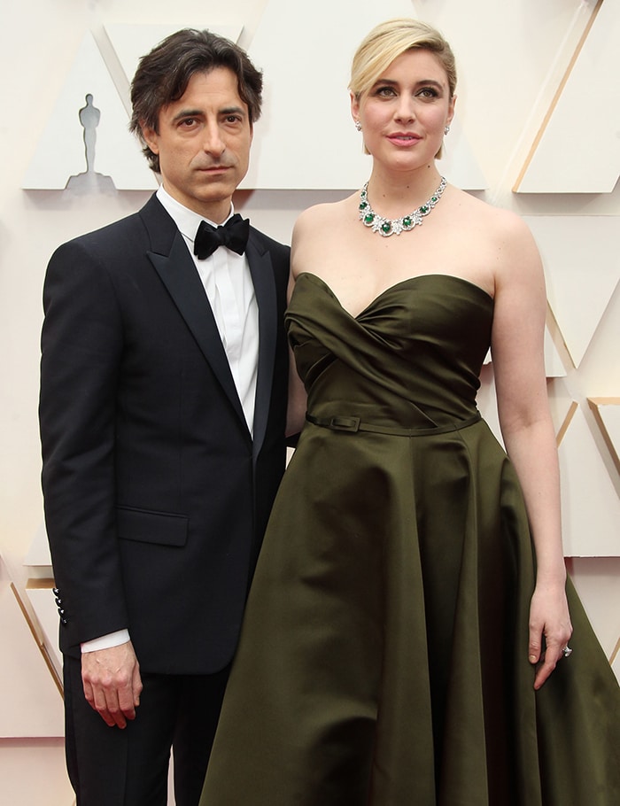 Noah Baumbach and Greta Gerwig make a striking pair on the Oscars red carpet, with Baumbach in a classic black Dior tuxedo and Gerwig radiating elegance in a strapless olive-green Dior Haute Couture gown adorned with Bulgari jewels