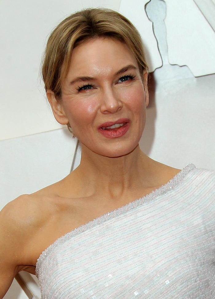 Renée Zellweger wears a chic center-parted updo and her signature soft pink makeup-look