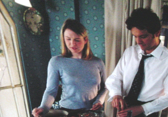 Renée Zellweger and Hugh Grant share a quietly charming moment in the kitchen during a scene from Bridget Jones’s Diary, highlighting the film’s signature blend of humor and heart