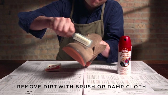 Gently brushing dirt from a suede shoe with a cleaning brush