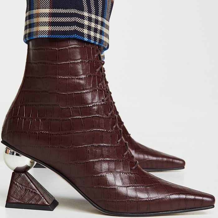 Selena Gomez’s burgundy croc-embossed Yuul Yie “Gloria Glam” boots feature the brand’s signature sculptural sphere-and-block heel for a bold, architectural finish