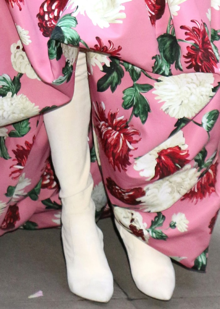 Celine Dion peeks out from beneath her Oscar de la Renta floral gown in white Ralph Lauren 'Tasita' thigh-high boots, whose sleek pointed toes and fitted silhouette lend a modern edge to the romantic ensemble