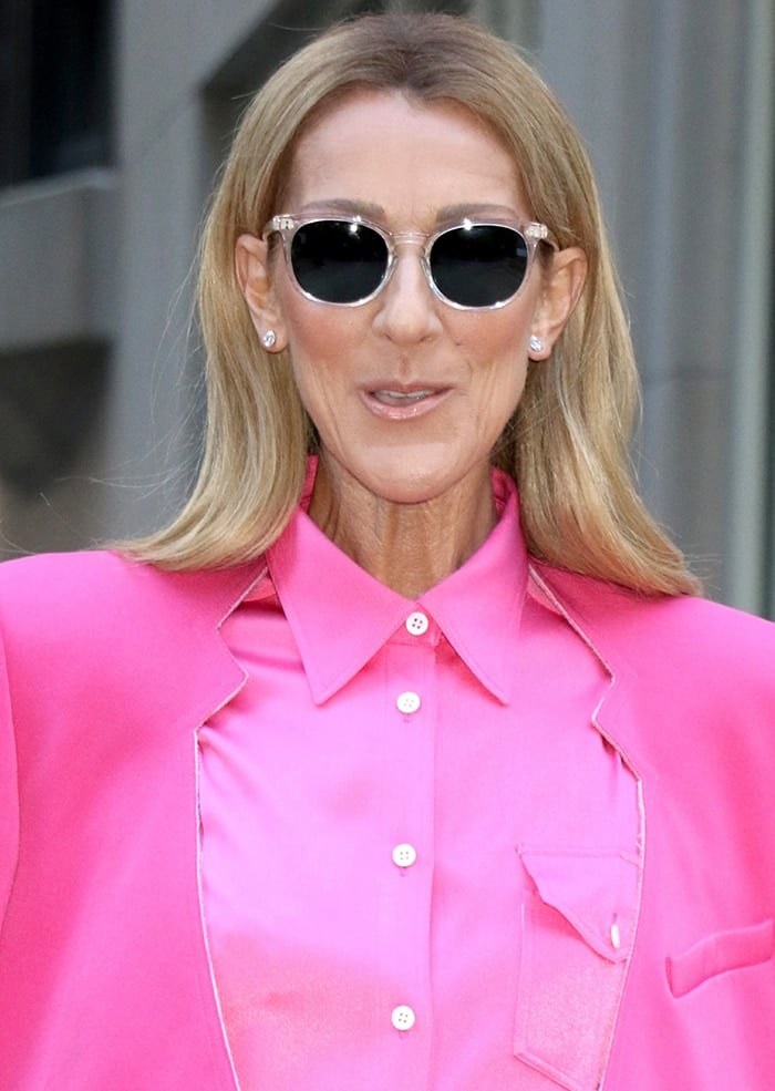 Celine Dion completes her Peter Do monochromatic look with diamond stud earrings, clear-framed sunglasses, and sleek, center-parted hair for a polished take on power dressing