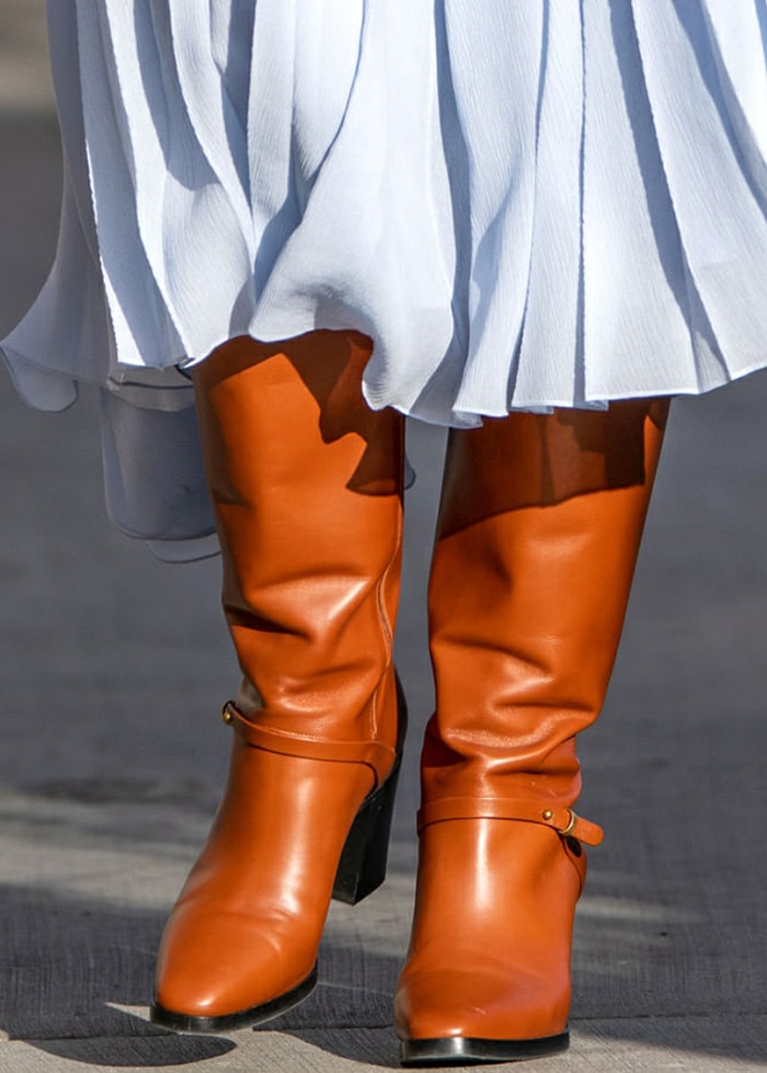A detailed look at Fanning’s chestnut-colored Gucci leather boots, featuring a block heel and minimalist strap detailing