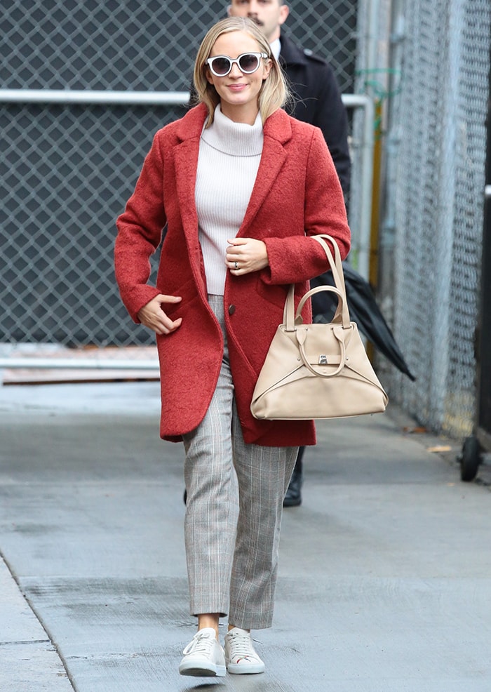Emily Blunt arrived at Jimmy Kimmel Live! on March 10, 2020, in a red Andrew Marc bouclé coat layered over a rib-knit turtleneck and plaid trousers, finishing the look with white Axel Arigato Clean Bird sneakers that added a casual, practical touch to the polished ensemble