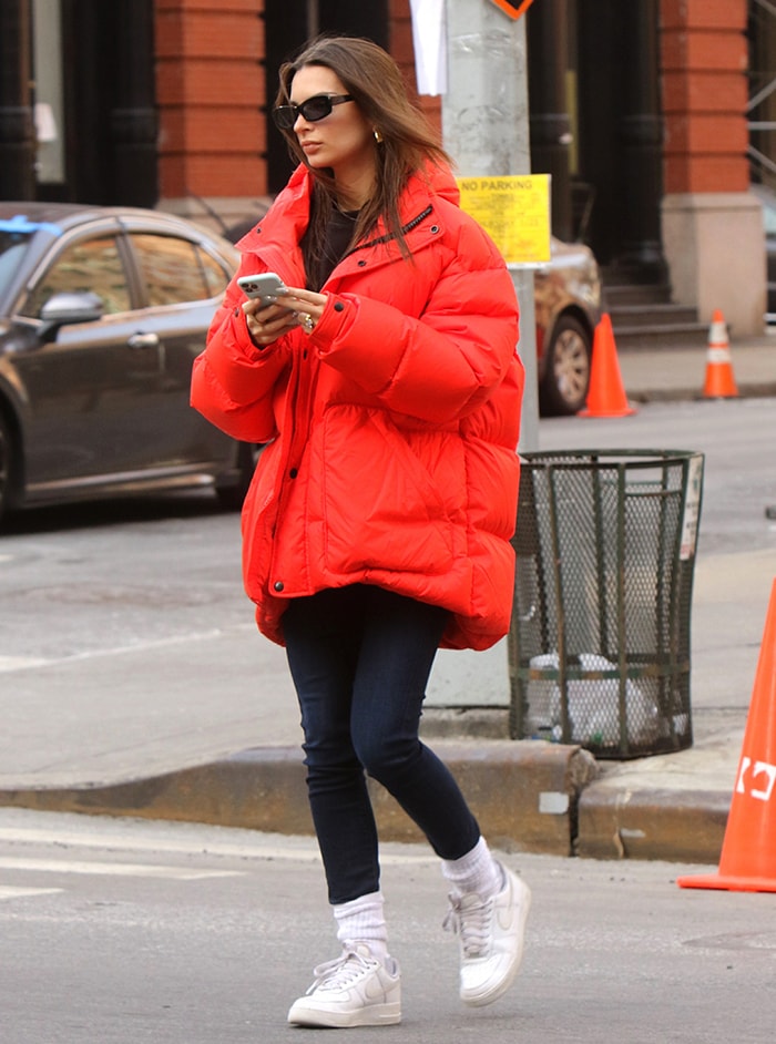 The oversized red puffer dominates Emily’s streamlined winter look, while white Nike Air Force 1s and scrunched crew socks add a classic streetwear finish