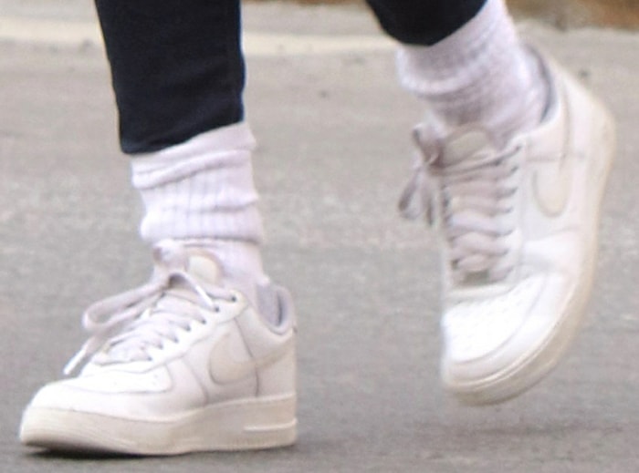 A close-up of Emily’s Nike Air Force 1 sneakers shows the monochrome white leather construction, signature Swoosh, and chunky rubber sole