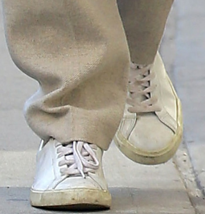 Emily’s Veja Esplar sneakers feature a minimalist white leather upper, tonal V branding, and an off-white rubber sole that complements her cream trousers