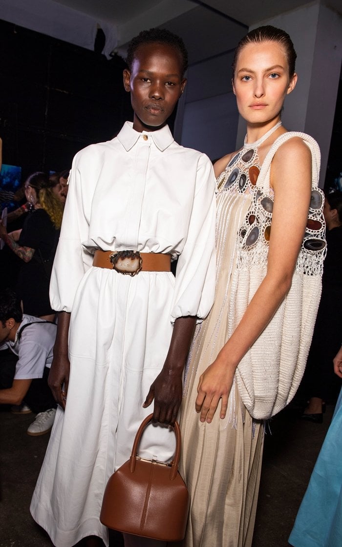 Gabriela Hearst's Ares leather maxi dress debuted with a pointed collar, batwing sleeves, an elasticated waist, and a statement agate-inspired belt buckle, reflecting the collection's utilitarian influences and premium craftsmanship