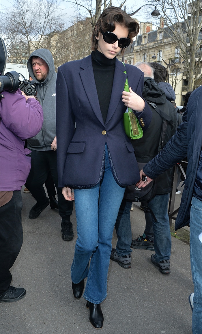Kaia Gerber steps out after the Miu Miu Fall/Winter 2020 show in Paris wearing an oversized navy Alexander Wang blazer with RE/DONE jeans, By Far ankle boots, and a green Marc Jacobs bag