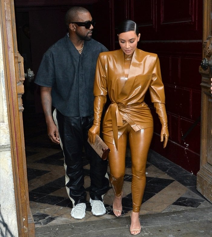 Kim Kardashian completes her custom caramel Balmain latex look with matching ankle-strap stiletto sandals, while Kanye West debuts the futuristic adidas Yeezy 451 prototype (later released as the Yeezy 450), creating one of Paris Fashion Week's most memorable footwear pairings