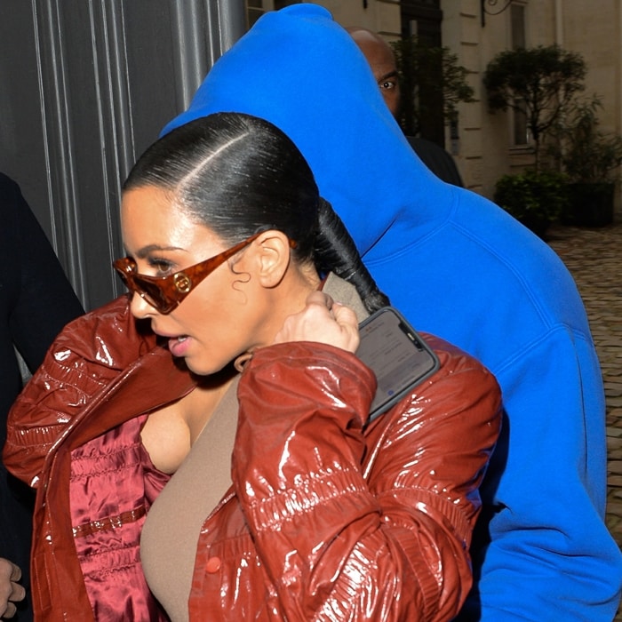 Kim Kardashian wears a glossy brick-red Bottega Veneta trench coat over a brown SKIMS bodysuit in Paris