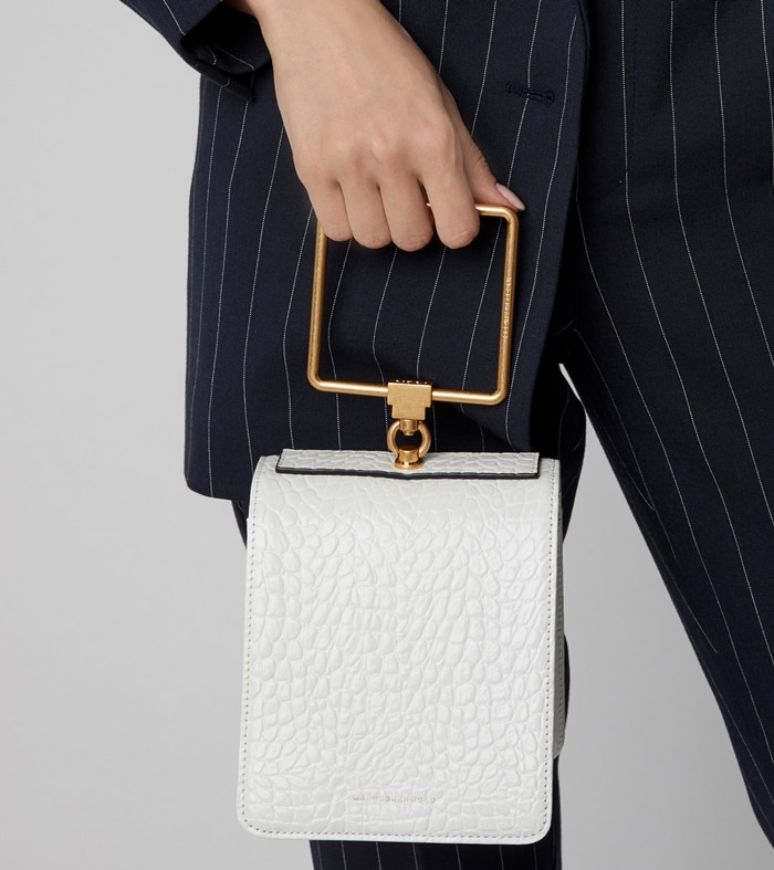 Marge Sherwood’s sculptural white Pump bag, distinguished by its croc-embossed finish and oversized gold-tone square handle